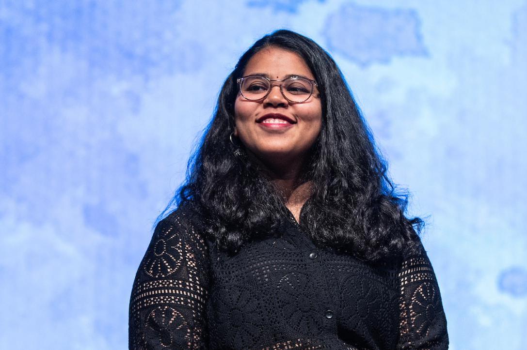 Student smiles on stage at a global celebration event.